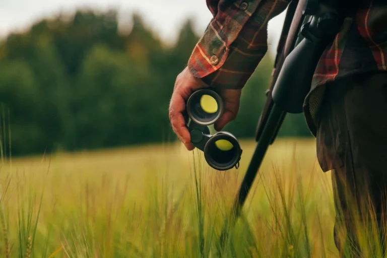 Cazador con prismáticos y escopeta en el campo